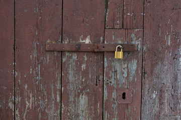 Old wooden doors locked with metal yellow lock. New yellow lock on old brown doors.