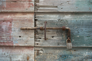 Old wooden doors closed with metal lock. Pale blue doors.