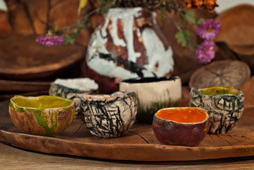 Clay pottery and ceramic products on a wooden table. Home workshop. Handmade with drawings and patterns.