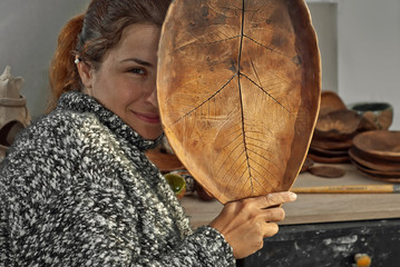 The girl paints pottery. Handmade products on the table at home workshop. Ceramic products with drawings and patterns.