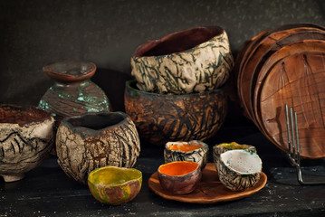 Clay pottery and ceramic products on a black wooden table. Home workshop. Handmade with drawings and patterns.