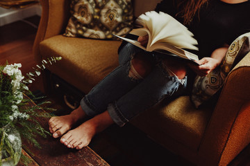 Cozy girl reading on yellow vintage couch