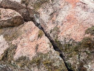 Large boulder, overgrown with moss with a crack