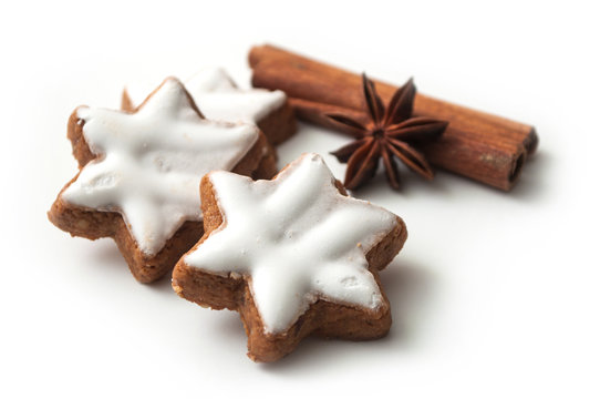 closeup of christmas biscuit shaped star with anise flower and cinnamon stick on white background