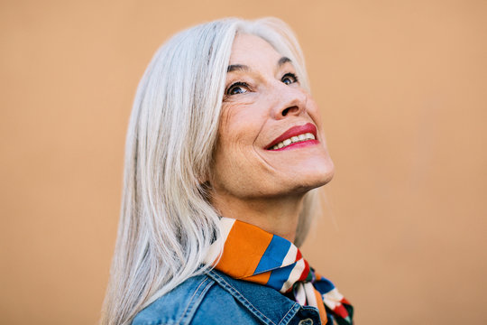 Portrait of a cool senior woman with grey long hair smiling.