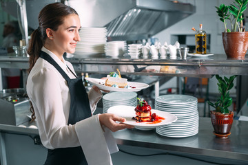 Waiter serving in motion on duty in restaurant. The waiter carries dishes.