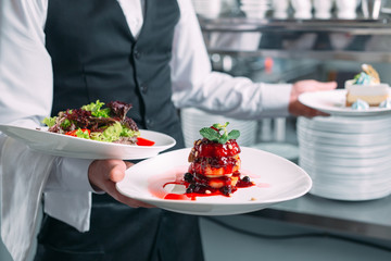 Waiter serving in motion on duty in restaurant. The waiter carries dishes