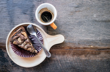 Top view of wooden plate of  browny cake and cup of coffee on wooden table