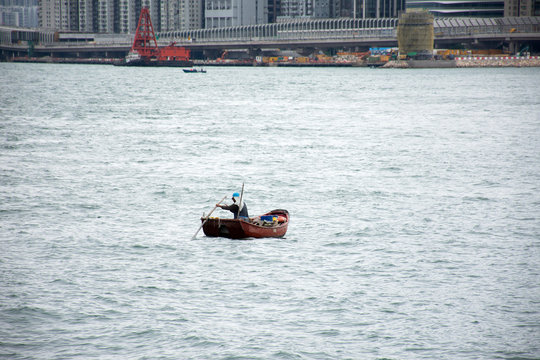 Chinese people paddle and floating wooden boat in the sea for catch fishing of Victoria Harbour in Hong Kong, China