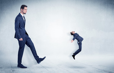 Big businessman kicking small businessman who is flying away with his briefcase on his hand
