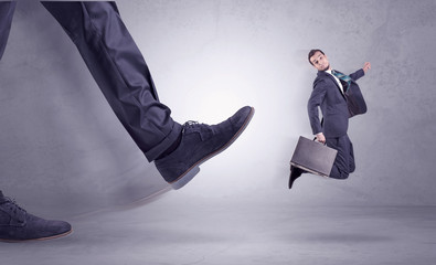 Deported from workplace, big foot kicking small businessman flying away
