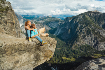 Traveler couple man and woman in Yosemite National Park, scenic view at Valley and Mountains from Upper Yosemite Falls, Overlook Trail, California, USA