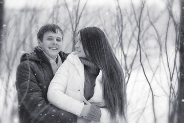 A loving couple on a winter walk. Man and woman on a date in the park in winter. Friends in a winter park