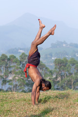 Indian man doing handstand outdoors in Kerala, South India