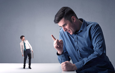 Young professional businessman being angry with an other miniature businessman 