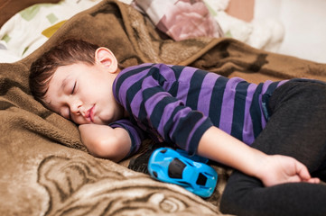 Obraz na płótnie Canvas A little boy played a lot with cars and tired and fell asleep in a sweet sleep