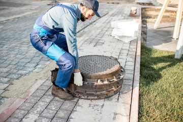 Workman in uniform mounting new road hatches at the residential area