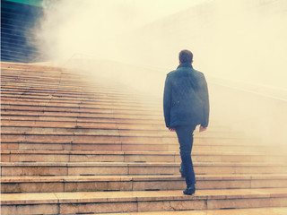 men climbing stairs in the fog to uncertain future