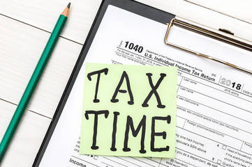 Sticker with phrase "TAX TIME" on tax form. Close up.