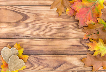 Naklejka na ściany i meble Autumn leaves with burlap heart on wooden background. Space for text.