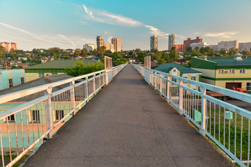 Fototapeta na wymiar Pedestrian viaduct. Beautiful perspective on background of city blue cloudy sunset sky