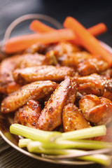 Roasted chicken wings served on a metal plate with carrots and celery