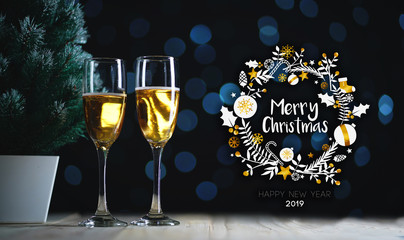 Merry Christmas Typography Art. Two Glasses of Champagne and Small Christmas Tree Dark Glow Lights Background.
