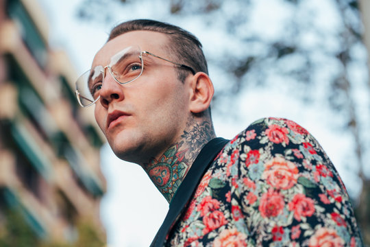 Tattooed handsome man with colourful flower jacket around the city.