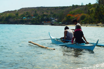 Fototapeta premium Tagpilatan, Batangas City, Philippines - May 18, 2016: young people enjoy riding on tiny small boat on sea