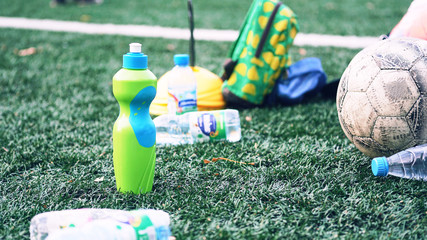 Plastic bottles with blurry soccer training equipment on artificial turf. It is waste from soccer training or football match.