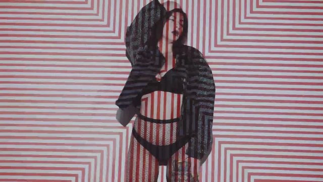 Portrait of woman in lingerie and jacket dancing with projected pattern on her. Music, nightclubs, shows and entertainment concept