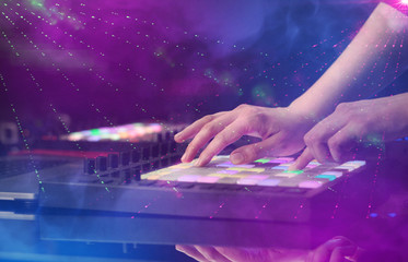 Fototapeta na wymiar Hand mixing music on midi controller with party club colors around 