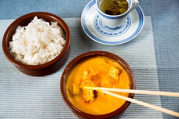 Chicken meat in mago sauce, rice and tea on blue.