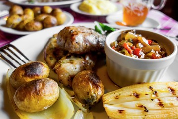 Fried chicken and pork meat, potato, vegetable,chicory on restaurant table.