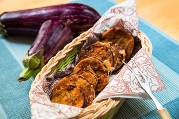 Basket with fried aubergine on table.
