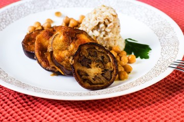 Fried aubergine, barley pearl and chickpeas on plate .