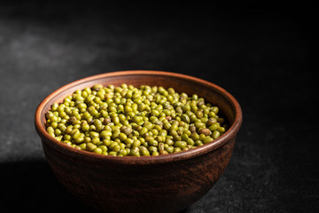 fresh mung beans in ceramic dishes against a dark stone background