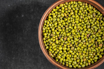 fresh mung beans in ceramic dishes against a dark stone background