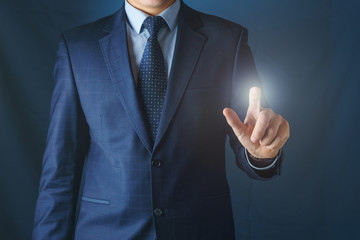 A man in a suit shows his index finger forward.