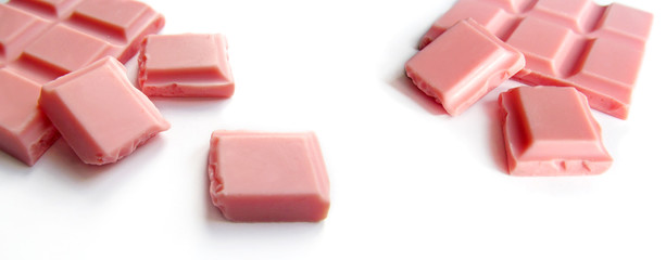 Pink chocolate bar and pieces isolated on white background. Close-up view of of luxury candy dessert.