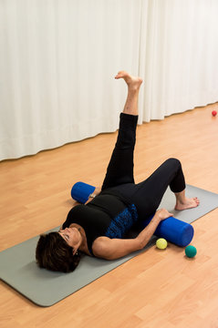 Senior woman using a foam roller in gym