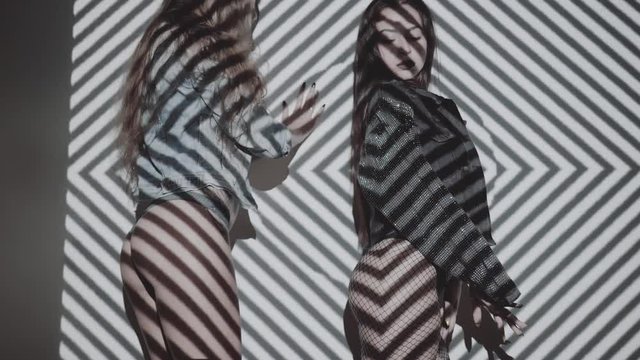 Two beautiful women in lingerie and jacket dancing with projected pattern on them. Music, nightclubs, shows and entertainment concept - video in slow motion