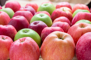 heap of unwashed unclean green and red apples mix on wooden background, top side view closeup