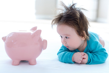 Baby boy with a piggy bank in childcare costs or savings theme