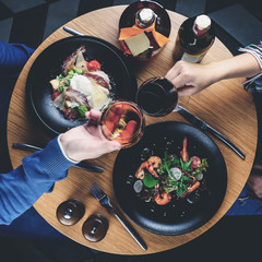 couple romantic dinner, close up of hand with glasses in a restaurant toned