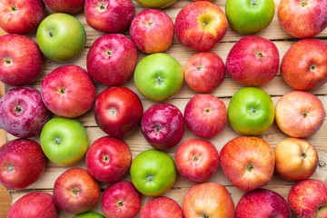 heap of unwashed green and red apples mix on wooden background, top side view closeup
