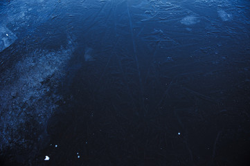 Thin transparent ice on the surface of the reservoir in late autumn