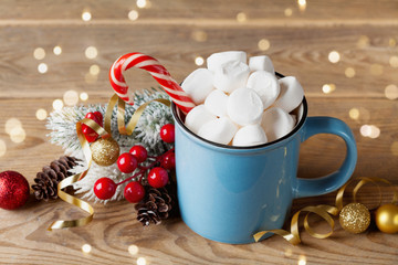Winter lifestyle with cup of hot cocoa with marshmallows and Christmas decoration on wooden background. Bokeh effect.