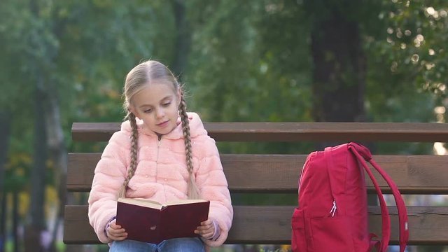 Curious little girl reading book after school, dreaming of fairytale prince