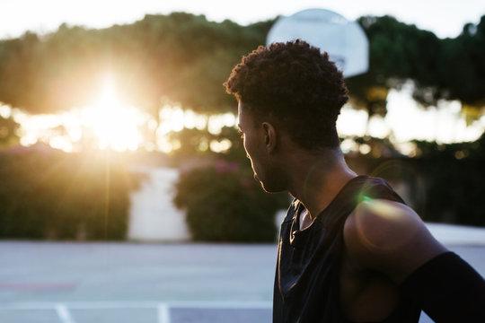 Young African American Man Playing Basketball On Outdoor Court.